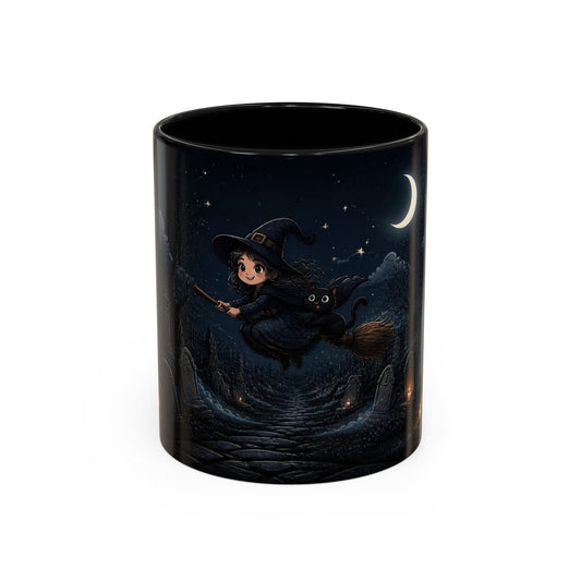 A black ceramic mug featuring a printed illustration of a young witch riding a black cat on a broomstick under a crescent moon and starry night sky.