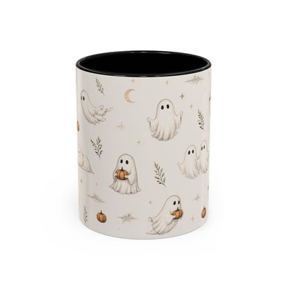A ceramic mug with a black interior and exterior pattern of cute cartoon ghosts, pumpkins, stars, and a crescent moon on a warm off-white background.