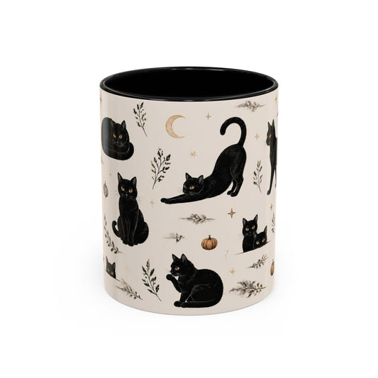 A ceramic mug with a cream-colored exterior patterned with black cats, a crescent moon, and small pumpkins, featuring a solid black interior, shown on a white background.