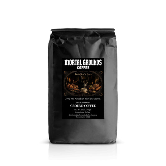 A black bag of Mortal Grounds Coffee, Family's Feast flavor, on a white background with a subtle reflection.